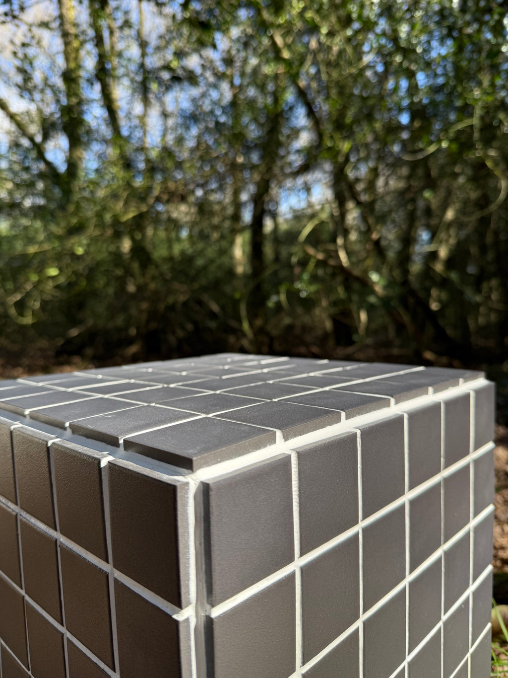Close-up of black porcelain mosaic tile and white grout finish on handmade cube side table 