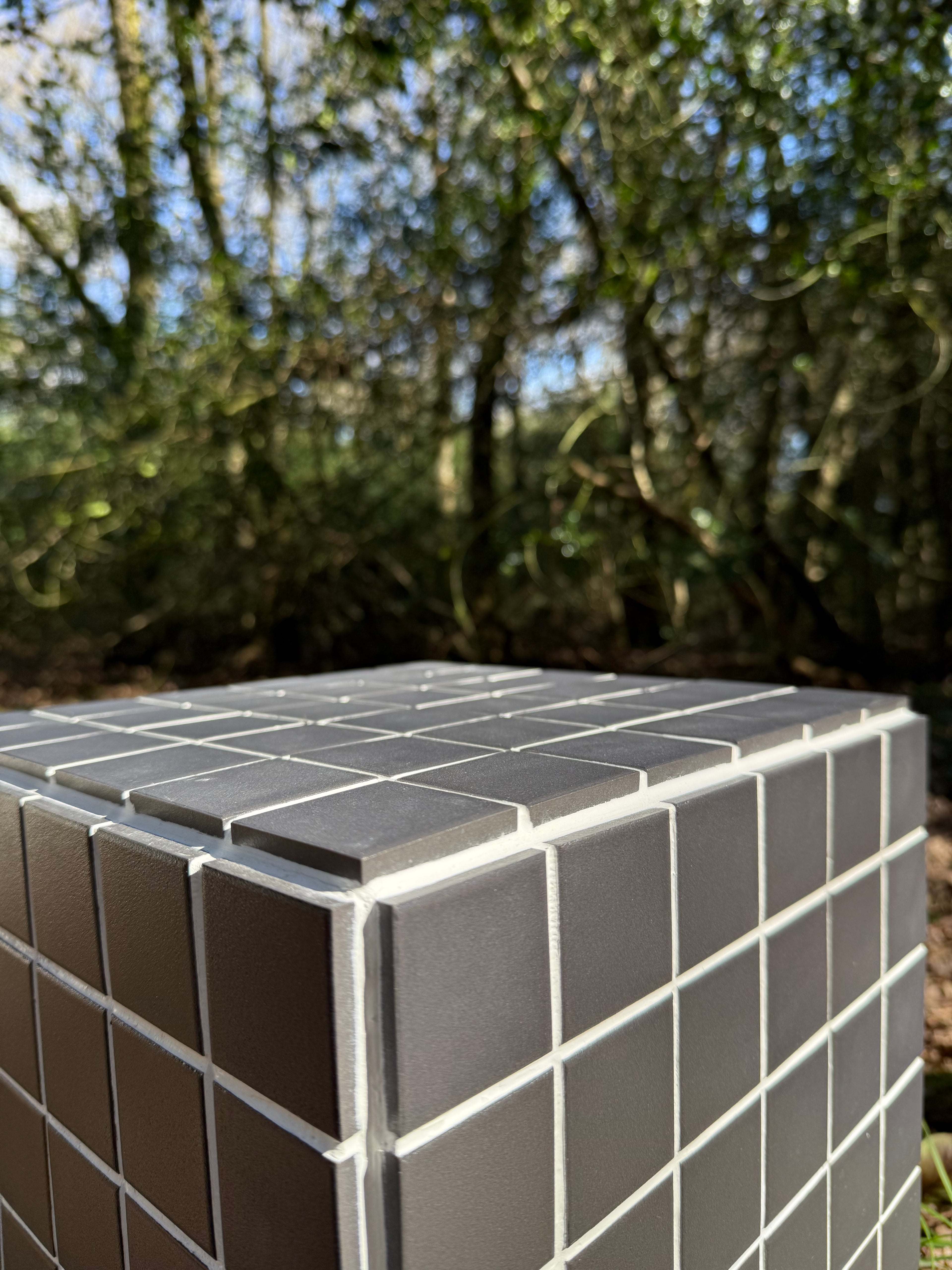 Close-up of black porcelain mosaic tile and white grout finish on handmade cube side table 