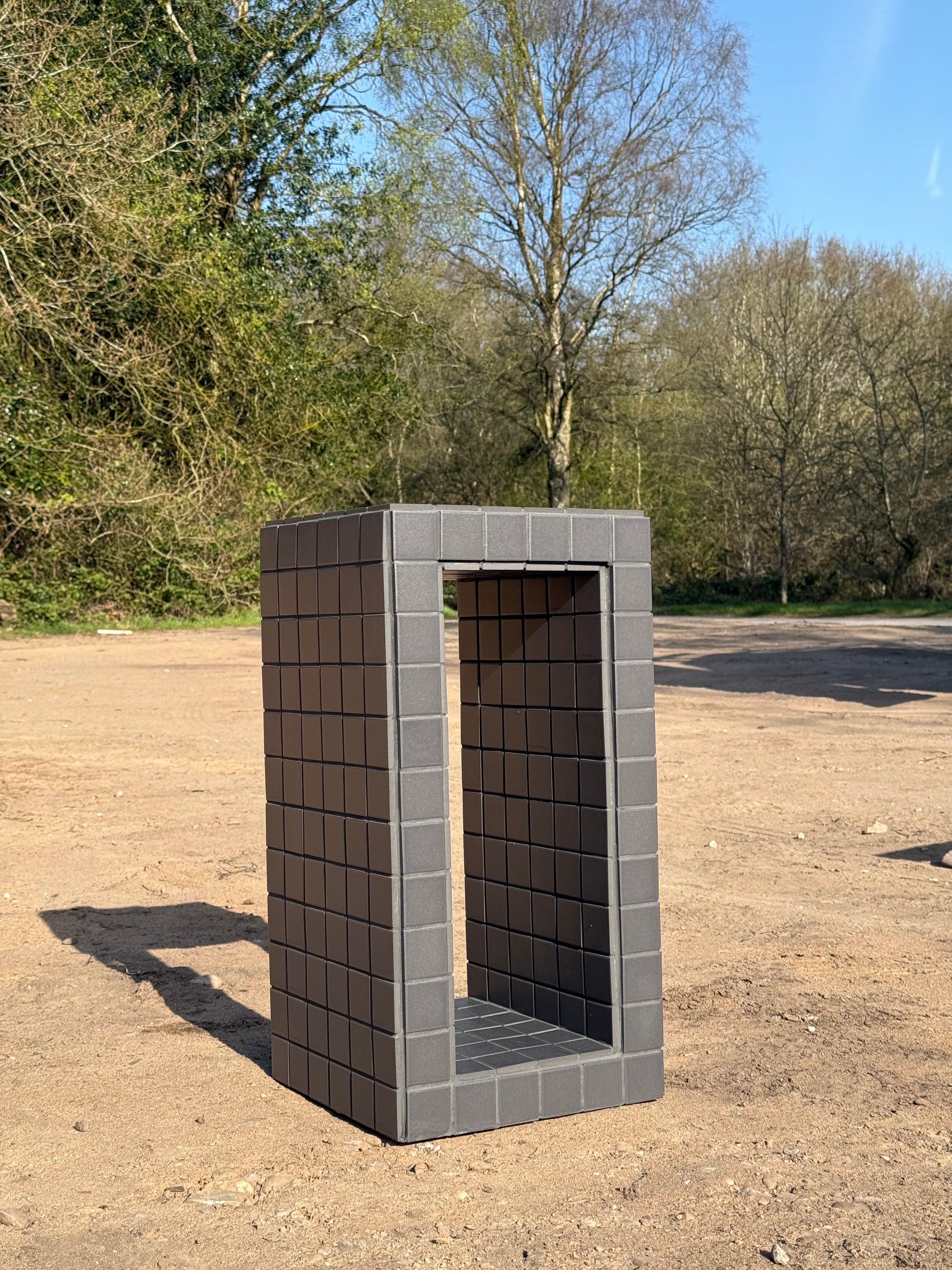 Side view of black porcelain mosaic tile open side table showing open centre shelf