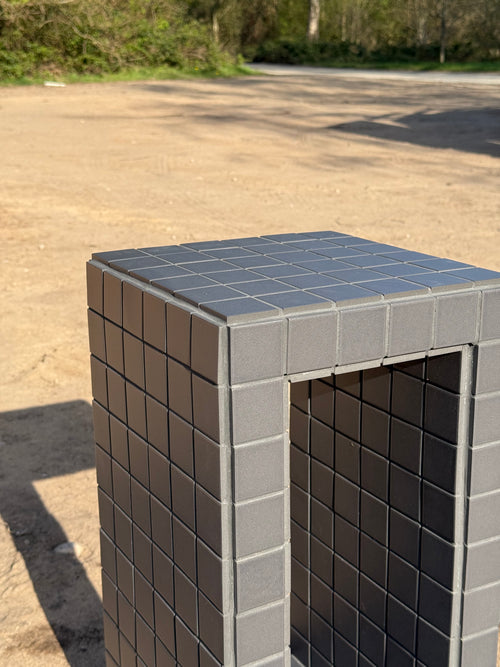 Close-up of black porcelain mosaic tile and black grout finish on handmade open side table